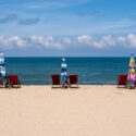 Beach with chairs and blue sea behind