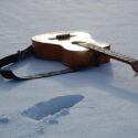 Guitar in the snow with foot step.