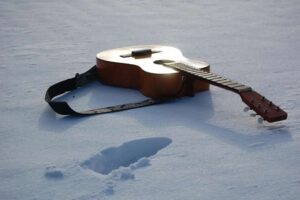 Guitar in the snow with foot step.