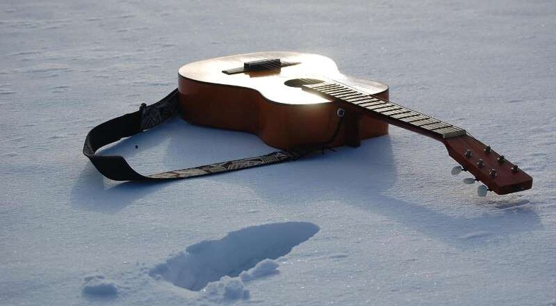 Guitar in the snow with foot step.